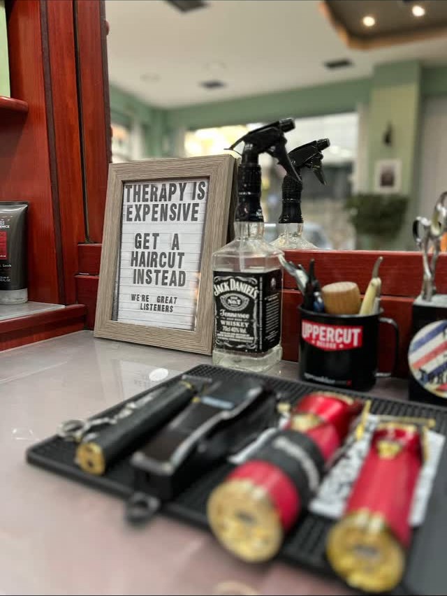 Η ταμπέλα «Therapy is expensive, get a haircut instead» στον πάγκο του Toronto Barber House, με τα εργαλεία και τα προϊόντα