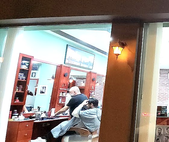 Ο χώρος του Toronto Barber House με τους μέντα τοίχους, τα μαονί έπιπλα και την τέχνη με τον ορίζοντα του Τορόντο