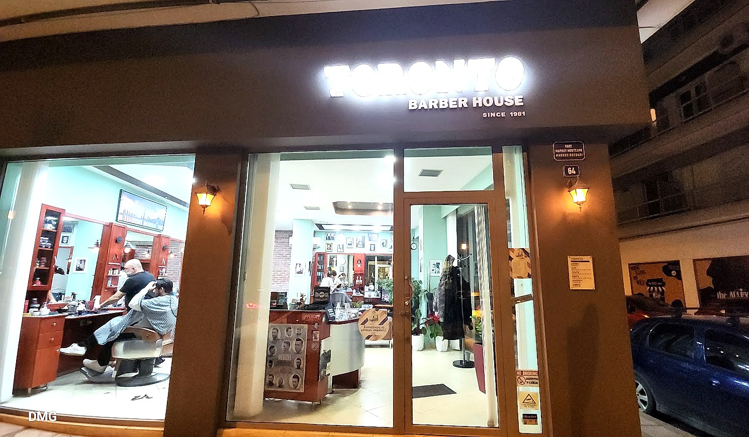 Η βιτρίνα του Toronto Barber House στη Θεσσαλονίκη, με την φωτεινή επιγραφή και το εσωτερικό του κουρείου